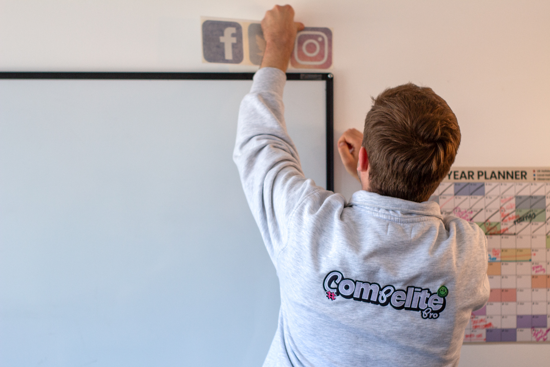 Compelite Pro strategist placing Facebook and Instagram icons above a whiteboard during a consultancy planning session