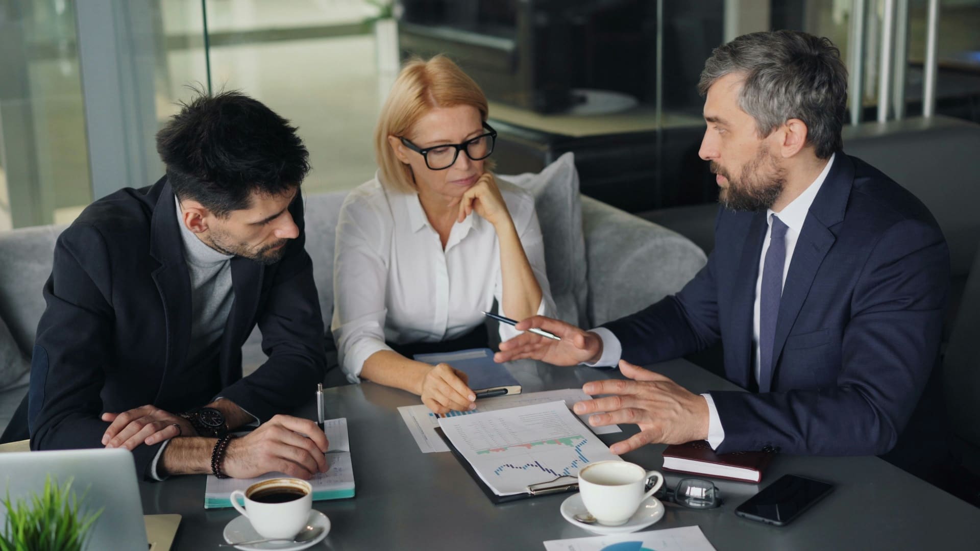 Financial advisors reviewing performance charts in a modern office meeting — social media agency for finance and accountancy firms
